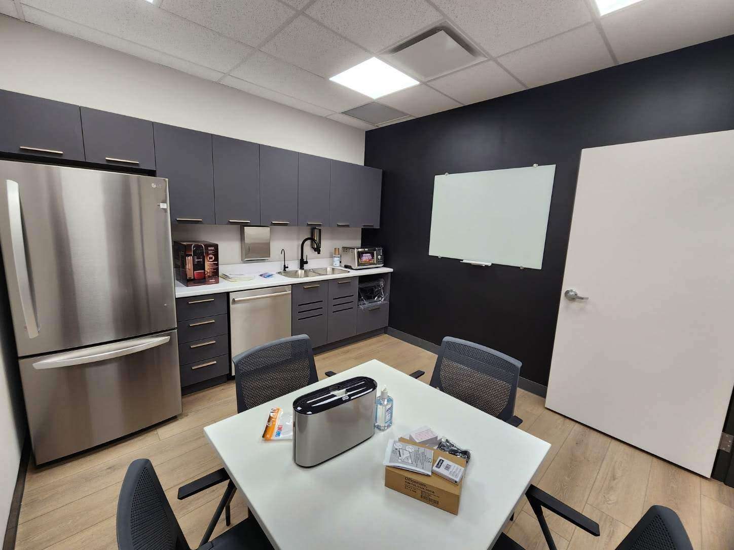 Modern commercial break room with a dark accent wall and full-height fridge